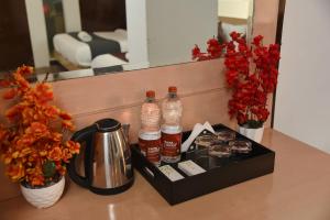a counter with two bottles of syrup and a tea kettle and flowers at Hotel The Emporio A Boutique Rooms Near Anand Vihar Vaishali Ghaziabad in Ghaziabad +23 photos