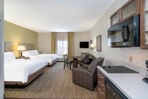 a hotel room with two beds and a desk at Candlewood Suites Auburn by IHG in Auburn