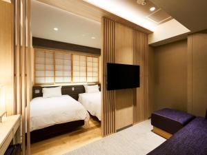a hotel room with two beds and a flat screen tv at Hotel Elcient Kyoto Hachijoguchi in Kyoto
