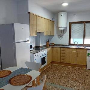 a kitchen with a white refrigerator and a table with chairs at María PLAYA ARENA NG in Peniscola