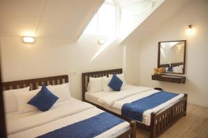 a bedroom with two beds with blue pillows and a mirror at Ivy Home in Nuwara Eliya