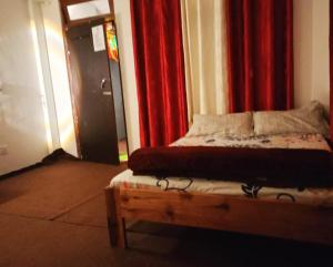 カリンポンにあるHeaven Valley Homestayの赤いカーテンが備わる客室のベッド1台