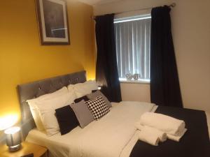 a bed with black and white pillows and a window at Apartment Sleeps 10 - Pets Parking Ev Charging in Walsall +36 photos