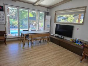 a dining room with a table and a tv at White House Pension in Pyeongchang 