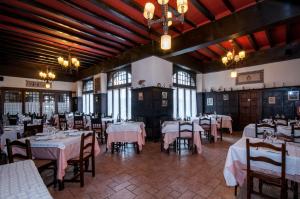 un comedor con mesas y sillas blancas y ventanas en Hostal Ayestaran II, en Lekunberri