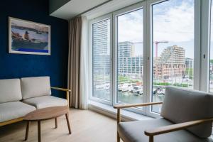 オーステンデにあるC-Hotels Burlingtonのソファと大きな窓のあるリビングルーム