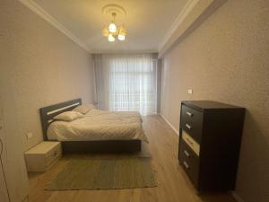 a bedroom with a bed and a dresser and a window at Caspian Mirvari in Sumqayyt