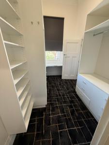 科布勒姆The Loft Cobram Hotel的步入式衣柜,配有白色橱柜和瓷砖地板