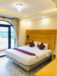 ein Schlafzimmer mit einem großen weißen Bett und lila Kissen in der Unterkunft Polin Hotel in Phumĭ Kaôh Tasai + 3 Fotos