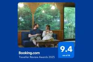 un uomo e una donna seduti su un divano di 野窓 Nomadノマド Tsuwano GuestHouse & Cafe Lounge a Tsuwano