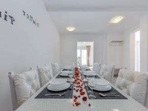 Una mesa de comedor larga con sillas blancas y flores rojas. en Quiet Villa with Soothing Spa, en Dramalj