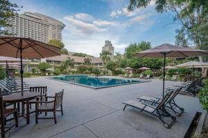 a pool with chairs and tables and umbrellas at Sunshine Garden Resort in North Pattaya
