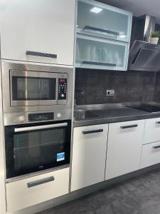a kitchen with white cabinets and a stove and microwave at Bonito apartamento en Aguadulce in Aguadulce