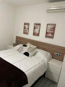 a bedroom with a large white bed with three pictures on the wall at Bonito apartamento en Aguadulce in Aguadulce