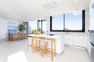 a kitchen with white counters and stools and windows at Gorvorana 3 - Piscina privada, BBQ in Realejo Bajo