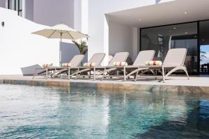 a group of chairs and an umbrella next to a swimming pool at Gorvorana 3 - Piscina privada, BBQ in Realejo Bajo