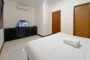 a bedroom with a white bed and a television at Spacious Luxury 2BR at Majesty Apartment By Travelio in Bandung