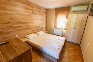 a bedroom with a bed and a wooden wall at Хотелски комплекс САНЯ in Apriltsi
