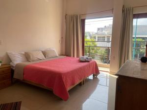 a bedroom with a bed with a red blanket and a window at Casita Cocoa in Santa Cruz Huatulco