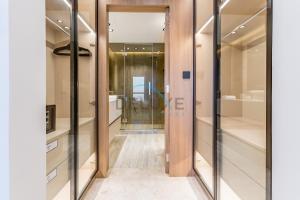 a walk in closet with glass doors and a hallway at Sea and Palm Jumeirah Views Just Steps from the Beach 2BR, Sadaf 6 , JBR by Deluxe Holiday Homes in Dubai