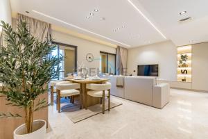 a dining room and living room with a table and chairs at Sea and Palm Jumeirah Views Just Steps from the Beach 2BR, Sadaf 6 , JBR by Deluxe Holiday Homes in Dubai