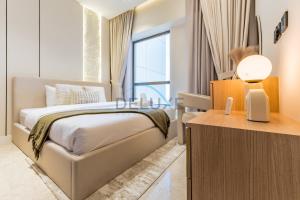 a bedroom with a bed and a desk with a lamp at Sea and Palm Jumeirah Views Just Steps from the Beach 2BR, Sadaf 6 , JBR by Deluxe Holiday Homes in Dubai +25 photos