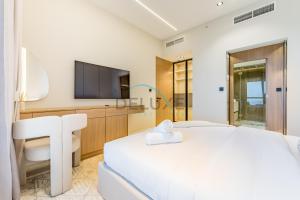 a white bedroom with a large bed and a tv at Sea and Palm Jumeirah Views Just Steps from the Beach 2BR, Sadaf 6 , JBR by Deluxe Holiday Homes in Dubai