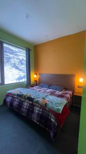 ein Schlafzimmer mit einem Bett und einem großen Fenster in der Unterkunft Cafe Alpenglow in Sissu