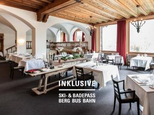 a restaurant with white tables and chairs and windows at Engadiner Boutique-Hotel GuardaVal in Scuol