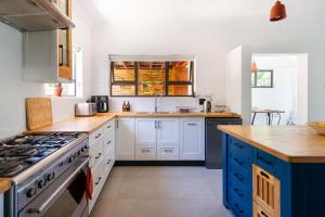 a kitchen with white cabinets and blue appliances at Seaside Family Villa in Wilderness