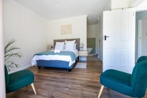 a bedroom with a bed and two blue chairs at Seaside Family Villa in Wilderness