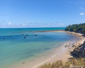 a beach with a bunch of people in the water at Suites Dupla beira mar Carapibus in Conde