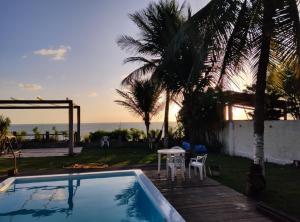 a swimming pool with a table and a view of the ocean at Suites Dupla beira mar Carapibus in Conde