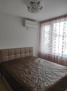 a bedroom with a bed and a chandelier at Апартамент Сандански Център in Sandanski