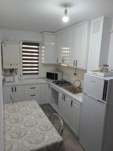 a kitchen with white cabinets and a sink and a table at apartament de inchiriat in loc Moinesti in Moineşti