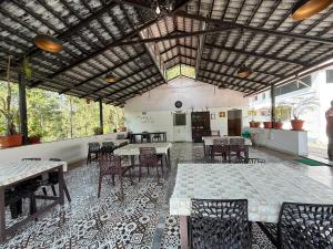 a dining room with tables and chairs and windows at Gadabanahalli Homestay in Vastāra