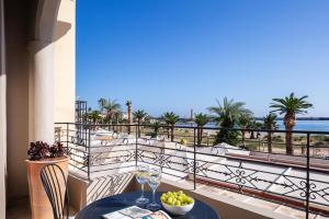 a table with wine glasses on a balcony with a view of the ocean at Chryssi 01, Stylish Seaside Spot in the Heart of Rethymno in Rethymno Town