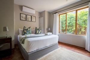 a bedroom with a bed and a large window at Raptors Wildlife Escapes in Hoedspruit
