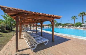 a group of lounge chairs under a pavilion next to a pool at 2 Bedroom Stunning Apartment In Isola Capo Rizzuto in Isola Capo Rizzuto