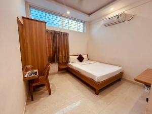 a bedroom with a bed and a desk and a window at Seema Palace Inn 1 km from Railwaystaion in Mysore