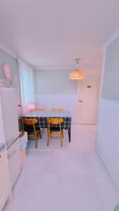 een keuken met een tafel, stoelen en een koelkast bij Yangyang Shim Stay in Yangyang
