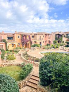 un patio con escaleras, arbustos y edificios en Residence Cala Moresca 34, en Golfo Aranci