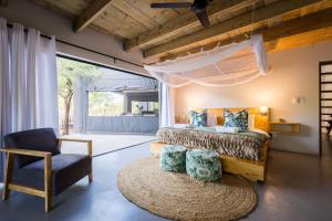 a bedroom with a bed and a chair and a rug at Raptors Luxury Farmhouse in Hoedspruit