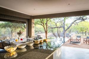a dining room with a table and a large window at Raptors Luxury Farmhouse in Hoedspruit