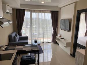 a hotel room with a bed and a desk and a television at Maikhao Beach Condominium in Ban Bo Sai Klang