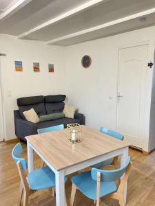 a table and chairs in a living room with a couch at La maison d'Oscar, 200m de la plage in Asnelles +7 photos