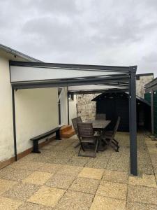 a pavilion with a table and chairs on a patio at La maison d'Oscar, 200m de la plage in Asnelles