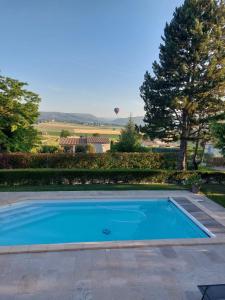 a blue swimming pool with a hot air balloon in the distance at Maison familiale à louer dans le Luberon in Dauphin
