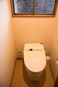 La salle de bains est pourvue de toilettes blanches et d'une fenêtre. dans l'établissement Ito Ryokuyu, à Itō