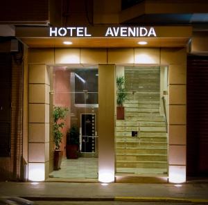 a hotel entrance at night with a sign on it at Hotel Avenida in Requena